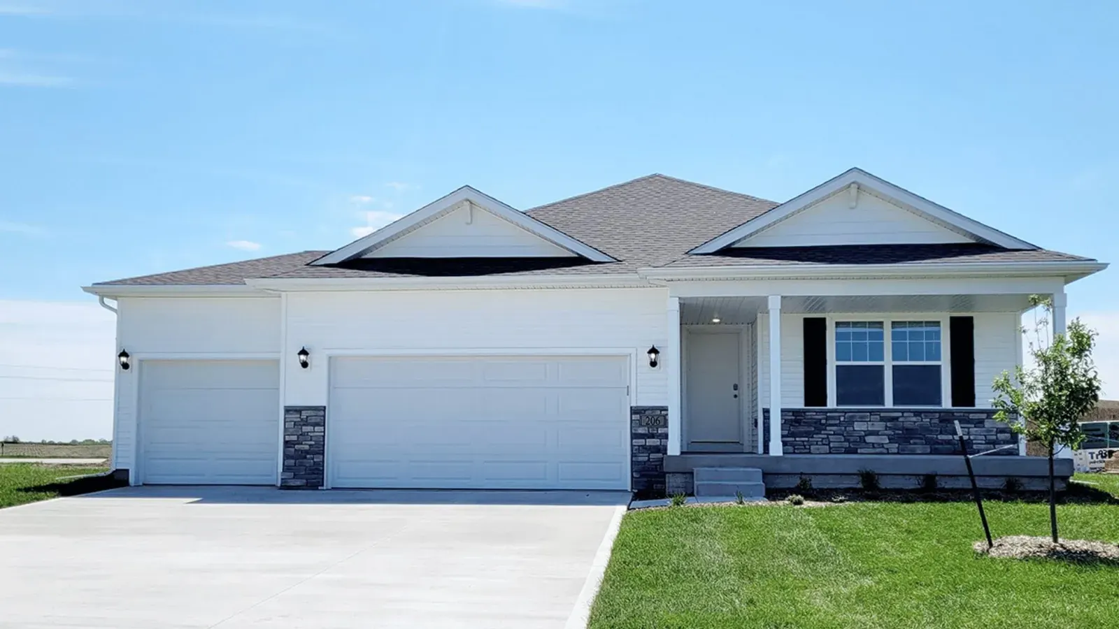 White ranch-style home with a three-car garage and stone accents on a new lawn