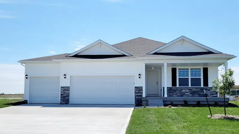White ranch-style home with a three-car garage and stone accents on a new lawn