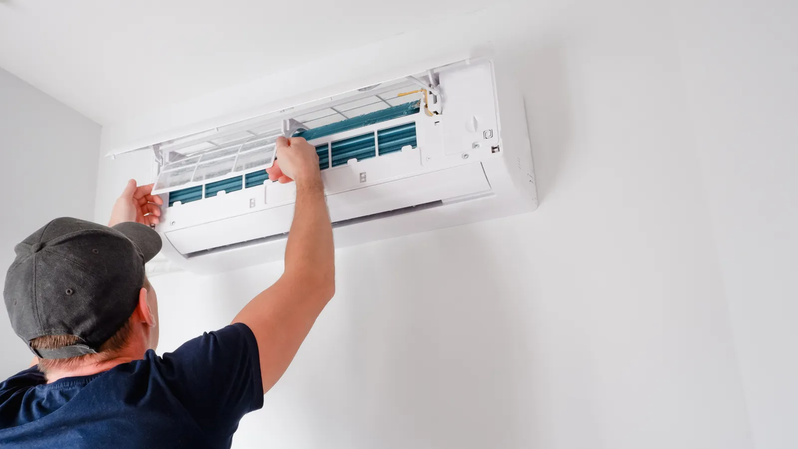 Technician servicing a wall-mounted ductless air conditioner