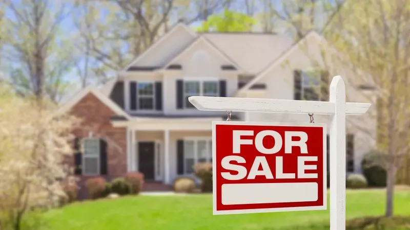 Brick two-story home with a red For Sale sign in the front yard
