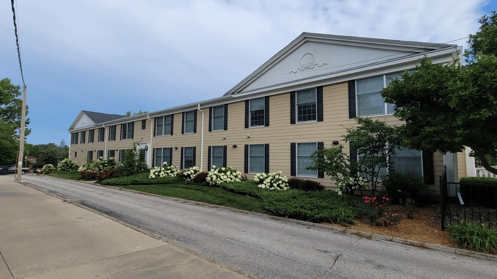 Two-story apartment building with a long front lawn along a street