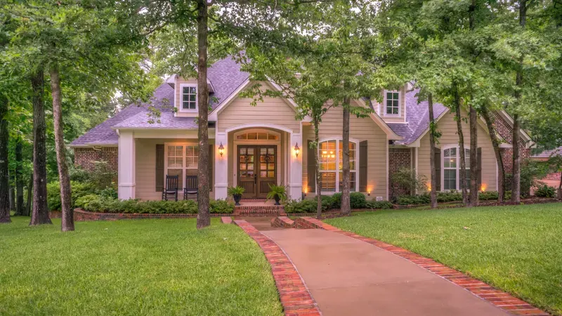 Two-story home with a brick walkway and a tree-lined front lawn