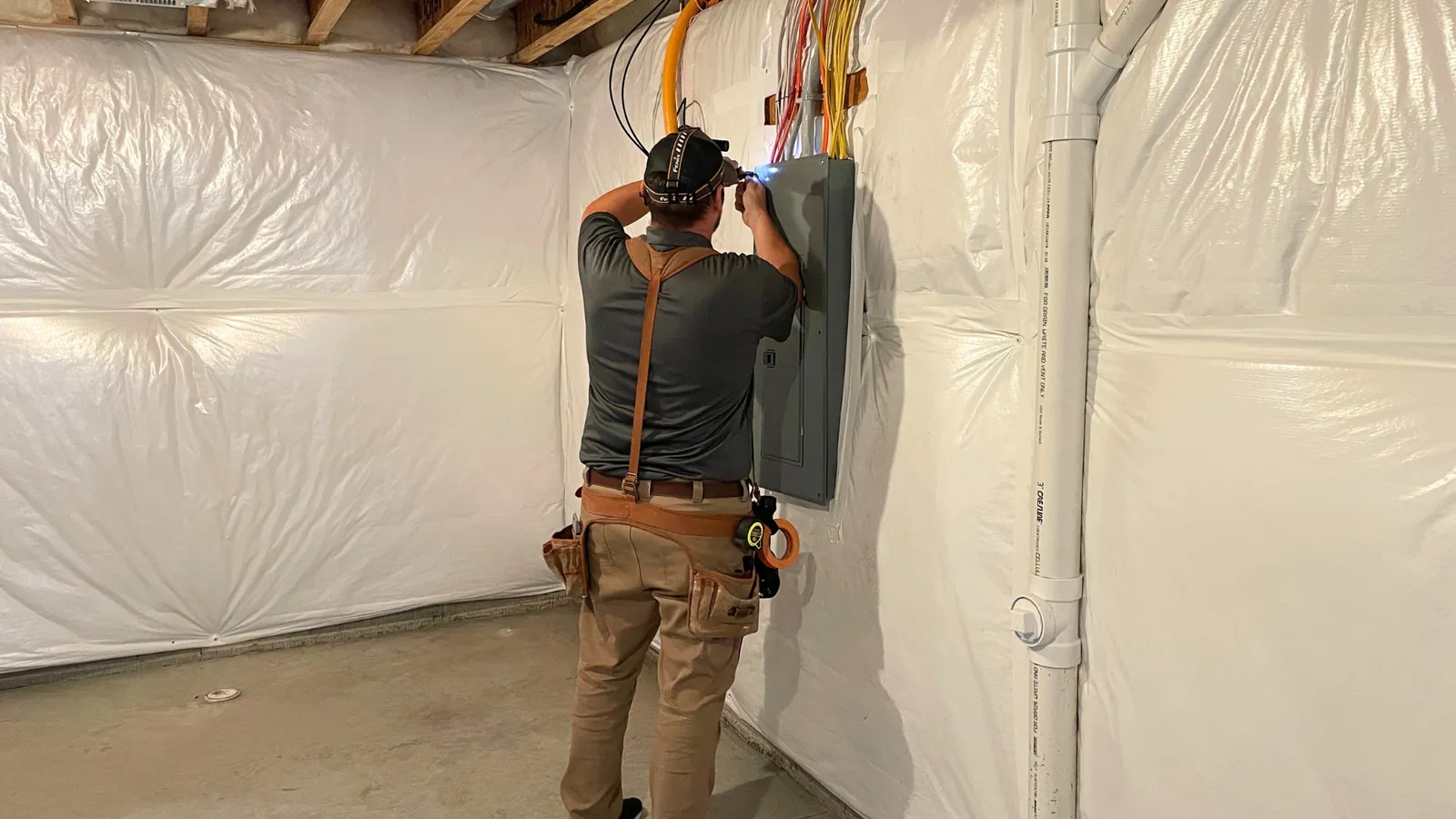 Inspector checking an electrical panel in an unfinished basement