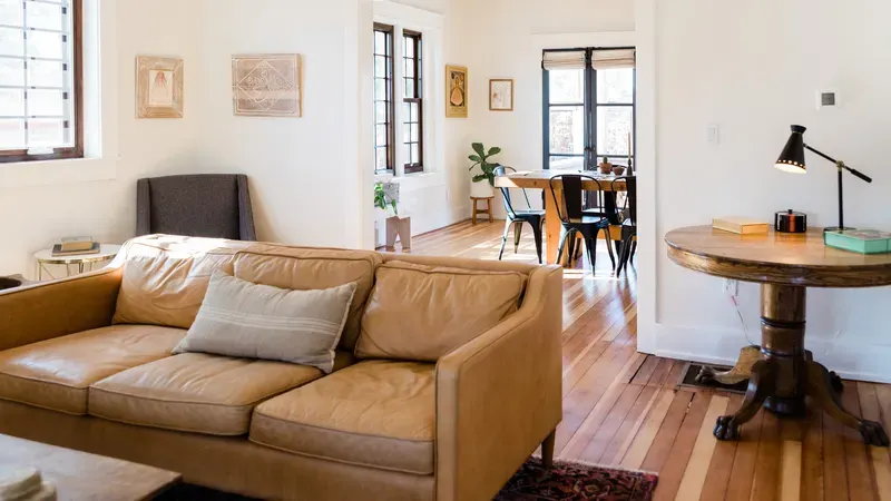 Bright living room with a leather sofa and a round wood table by the window