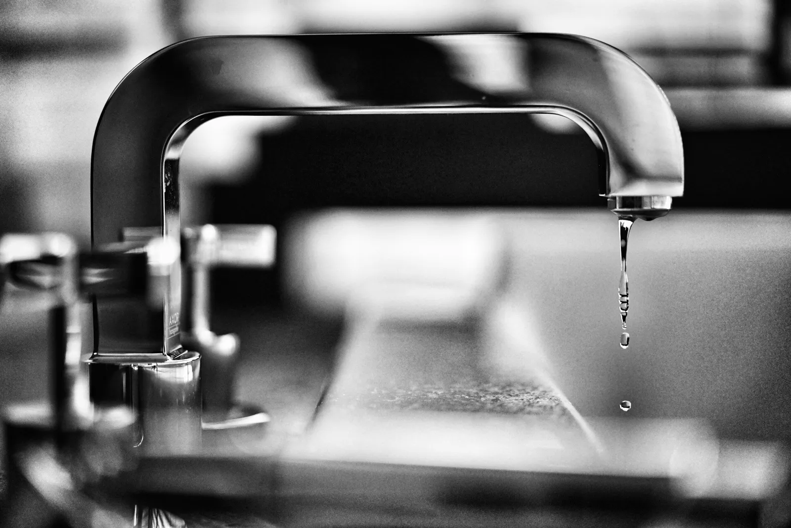 Black-and-white close-up of water dripping from a faucet