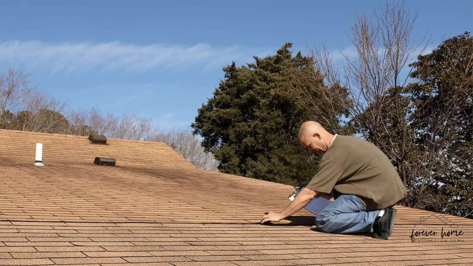Inspector kneeling on a roof to examine the shingles