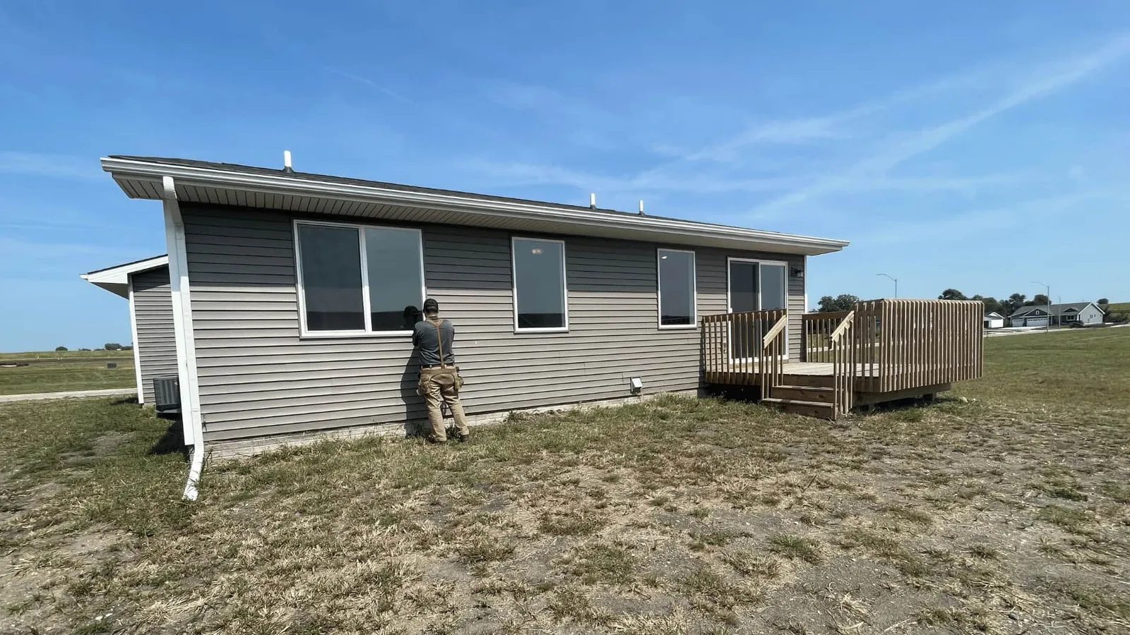 Inspector examining the siding of a gray ranch home
