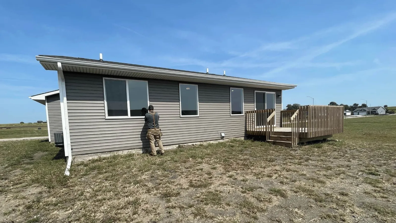 Inspector examining the siding of a gray ranch home