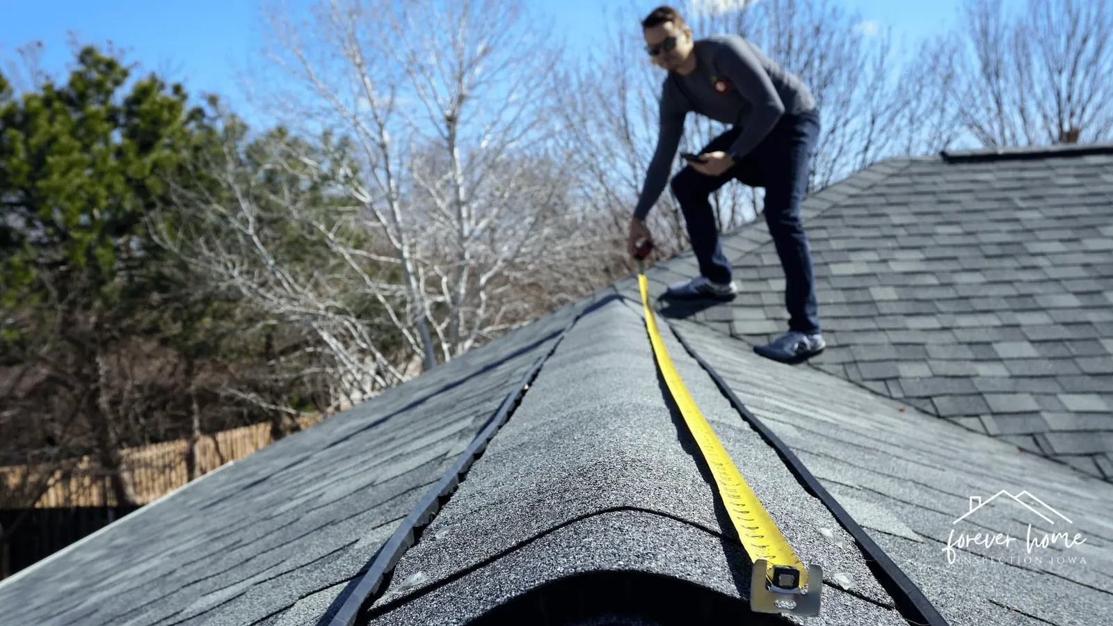 Inspector measuring along a roof ridge with a tape measure