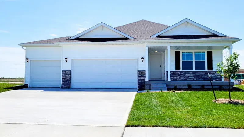 White ranch-style home with a three-car garage and stone accents on a new lawn