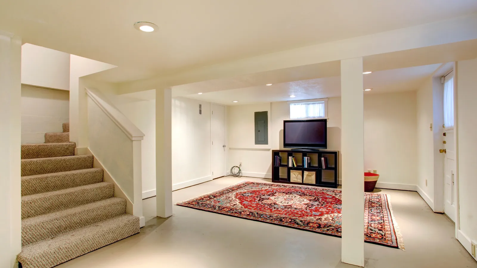 Finished basement with carpeted stairs, a rug, and a TV wall