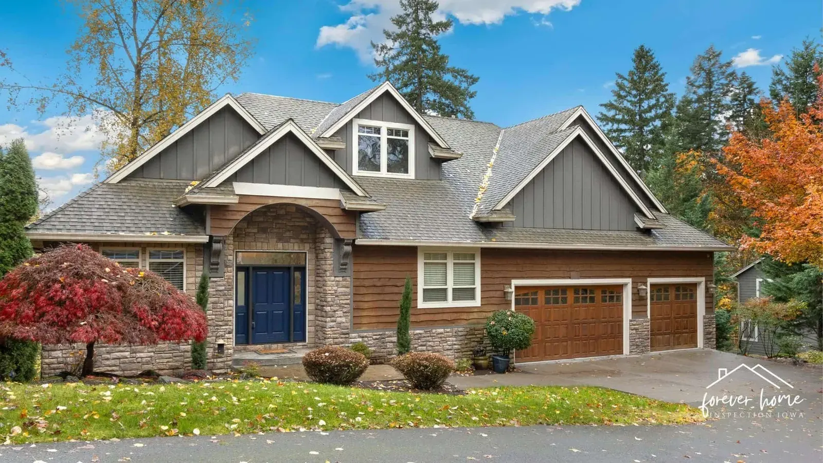 Two-story stone and siding home with a three-car garage and fall trees