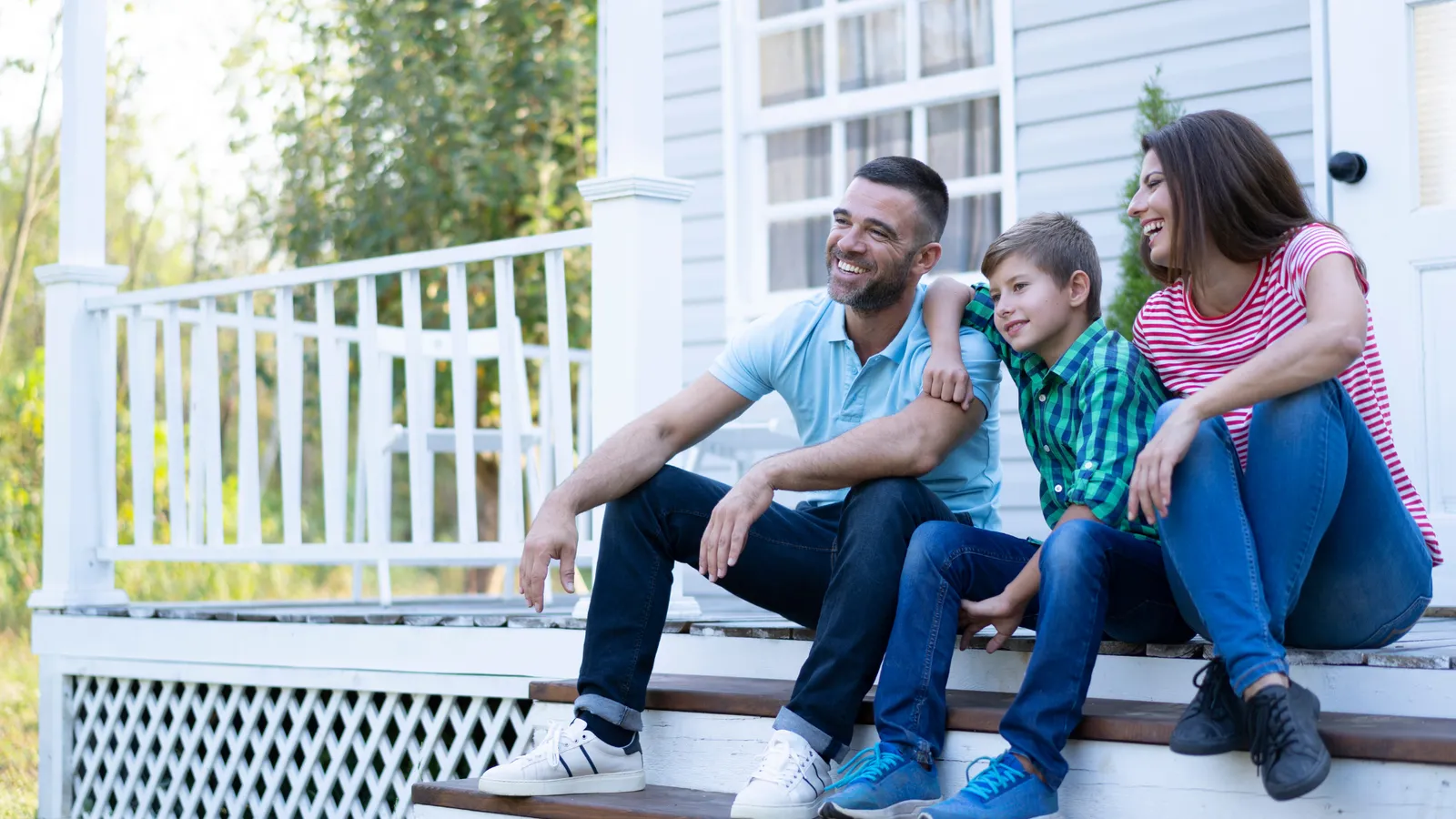 Family of four relaxing on the front porch steps of their home