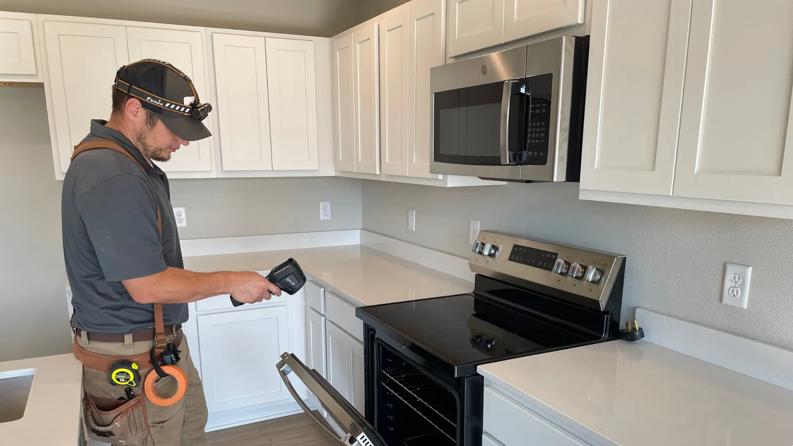 Inspector using a thermal camera in a new kitchen
