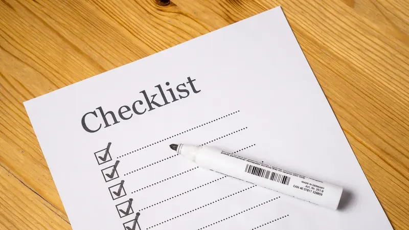 Checklist with ticked boxes and a marker on a wood table