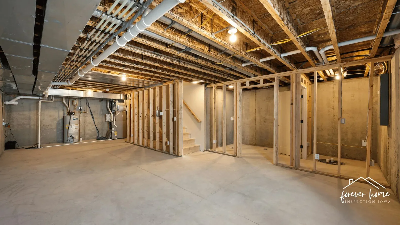 Unfinished basement with open ceiling joists and framed walls