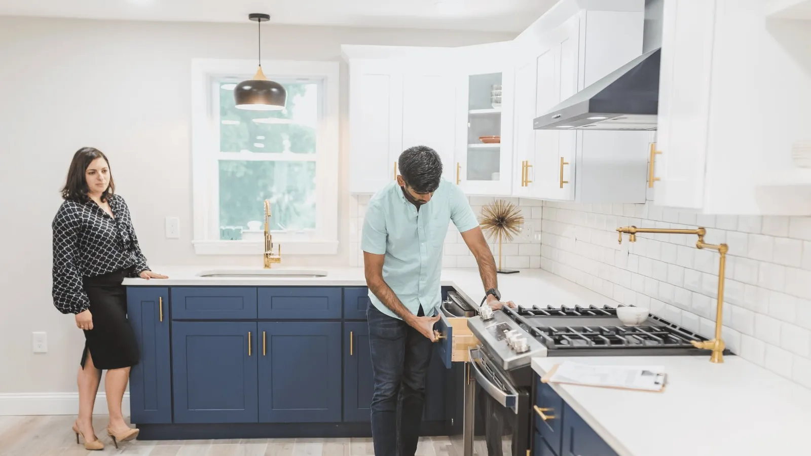 Inspector looking at a kitchen range while a woman watches
