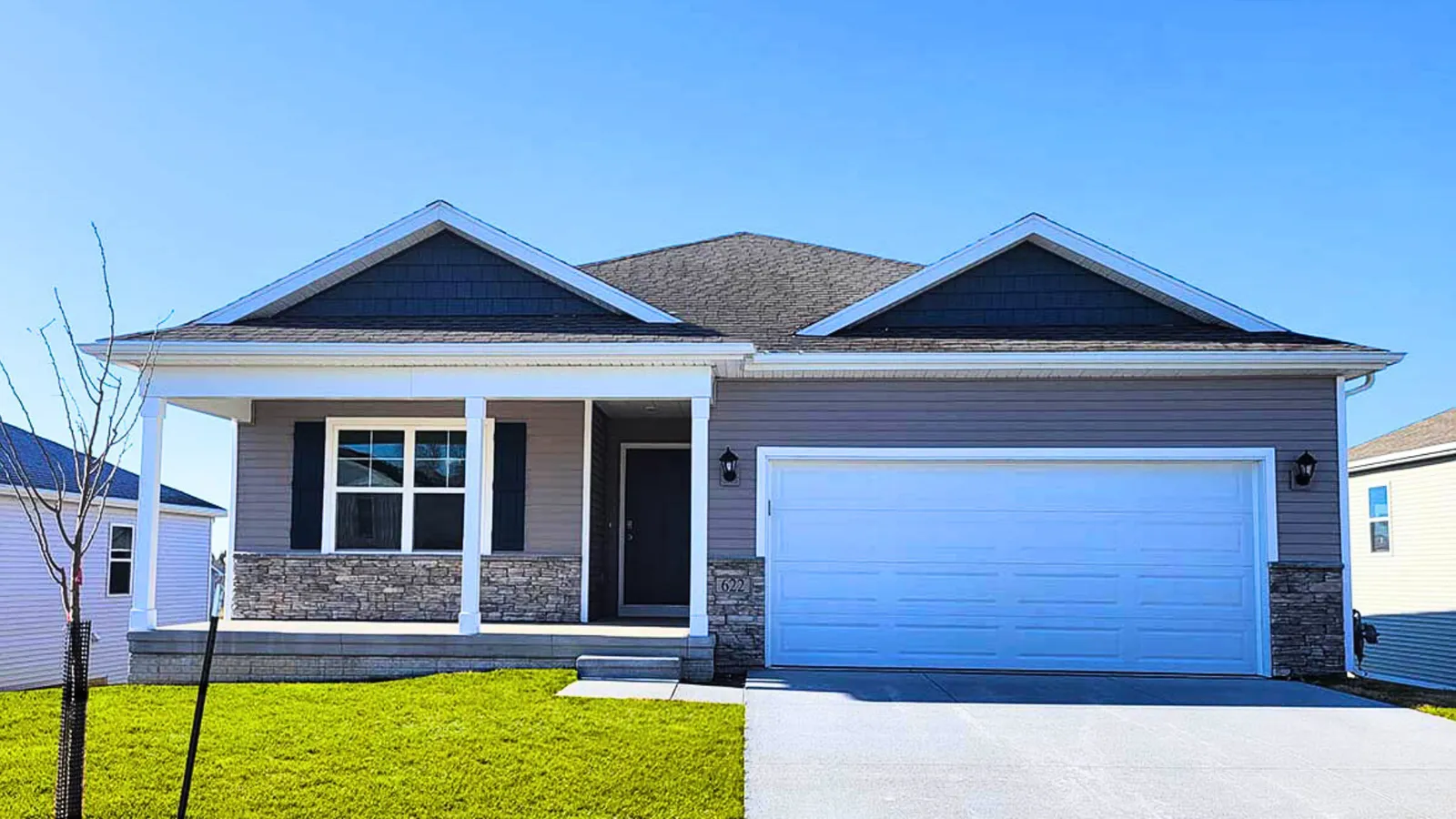 Newly built ranch home with blue siding, stone accents, and a two-car garage