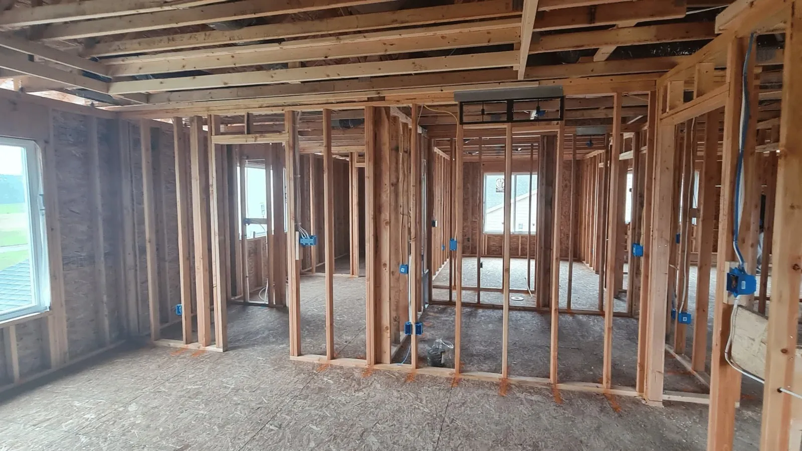 Open stud walls and rough-in wiring inside a home before drywall
