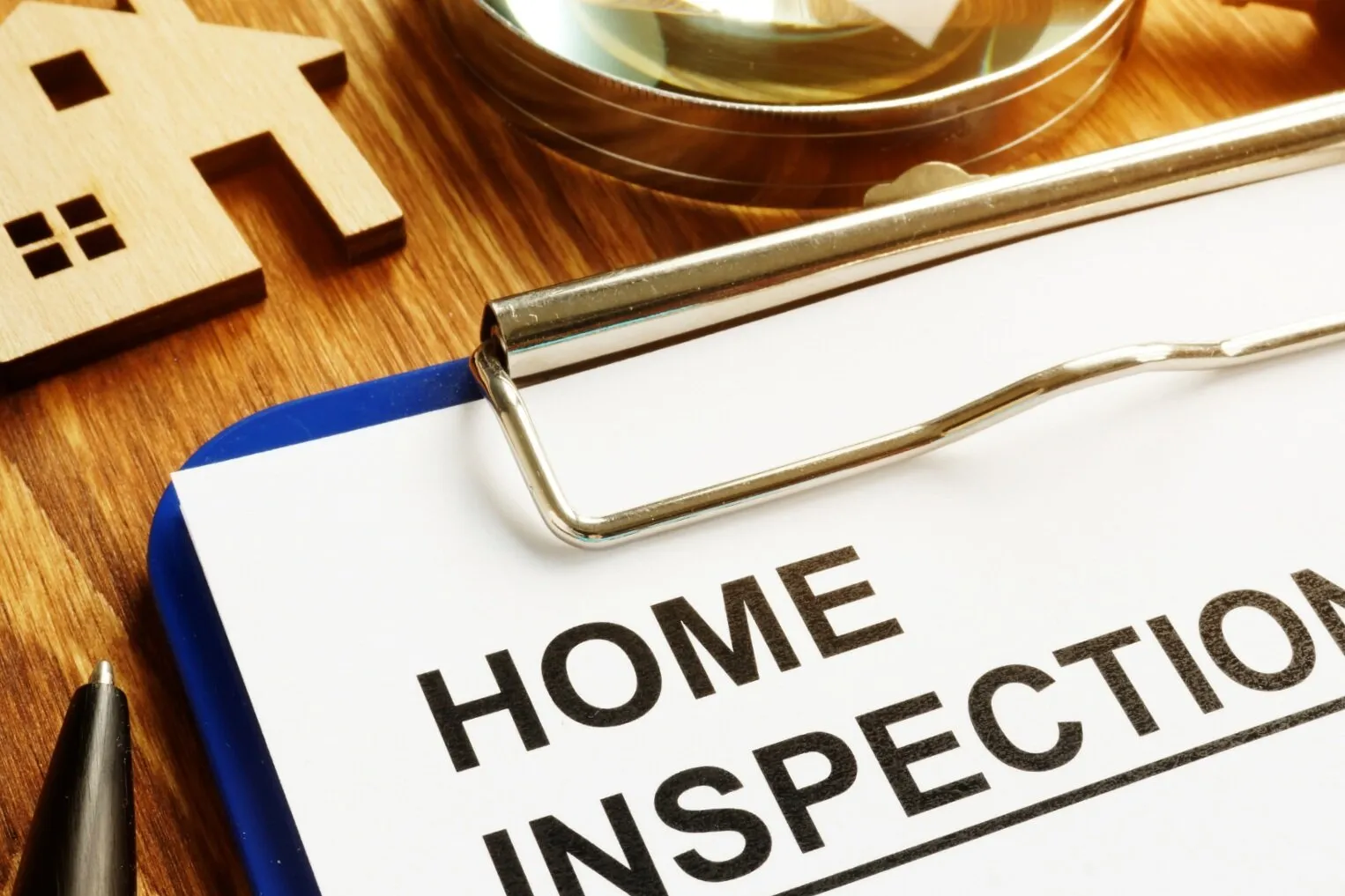 Clipboard with a Home Inspection form beside a small model house