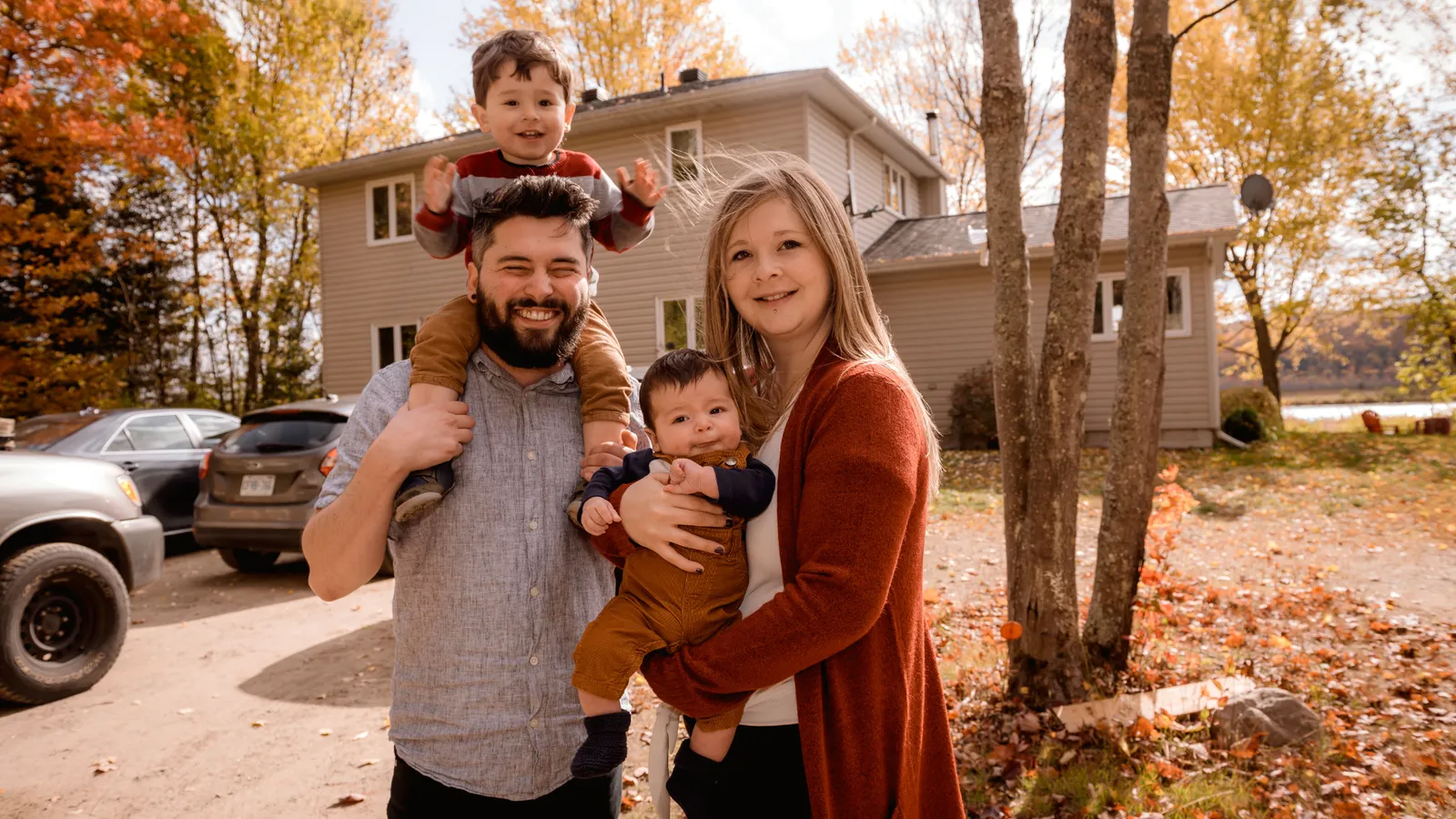 Family of four standing in their front yard in the fall