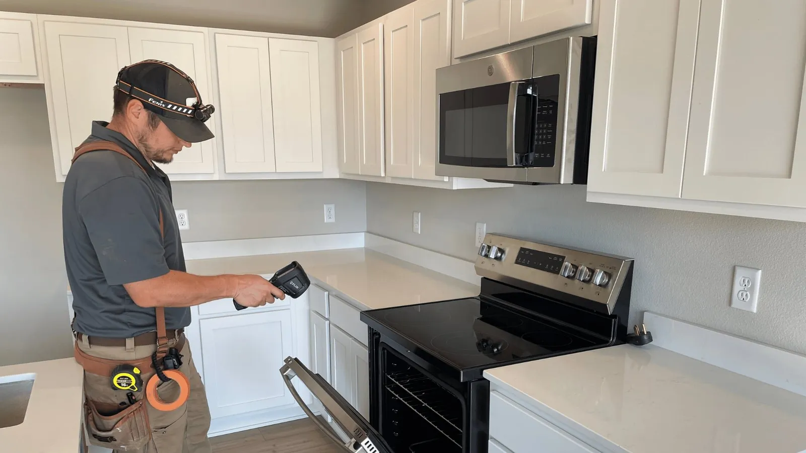 Inspector using a thermal camera in a new kitchen