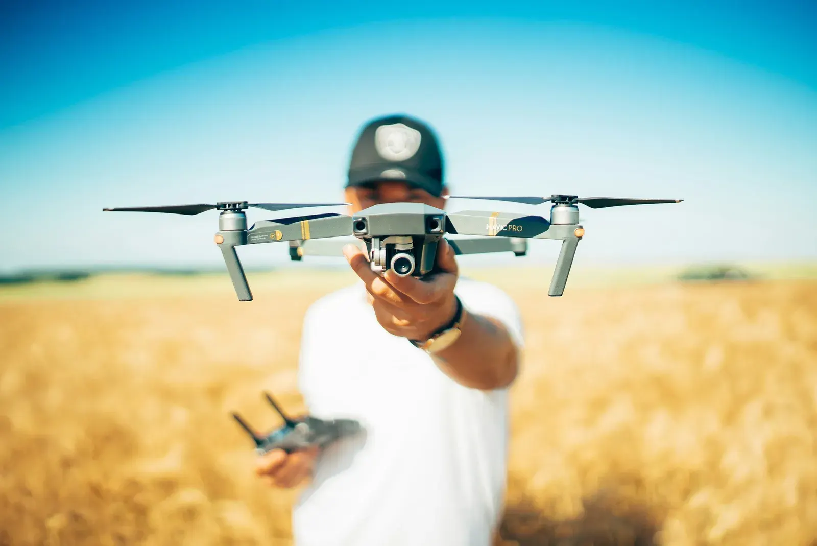 Person flying a camera drone over a wheat field