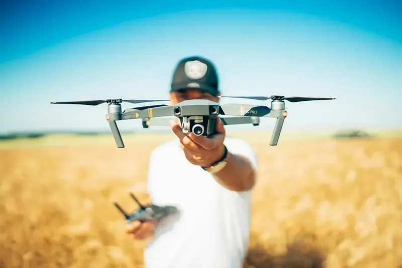 Person flying a camera drone over a wheat field