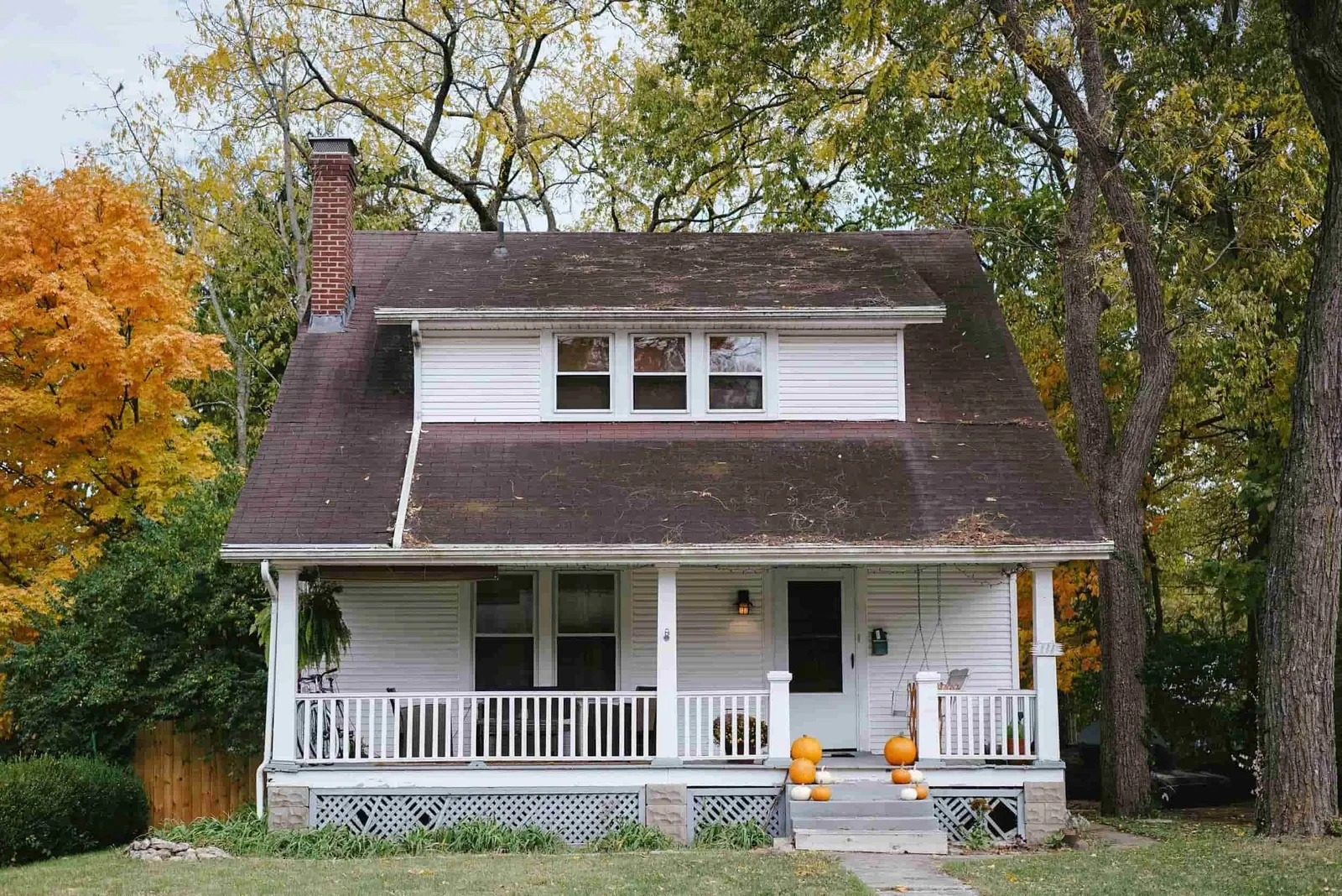Older two-story home with a front porch surrounded by trees