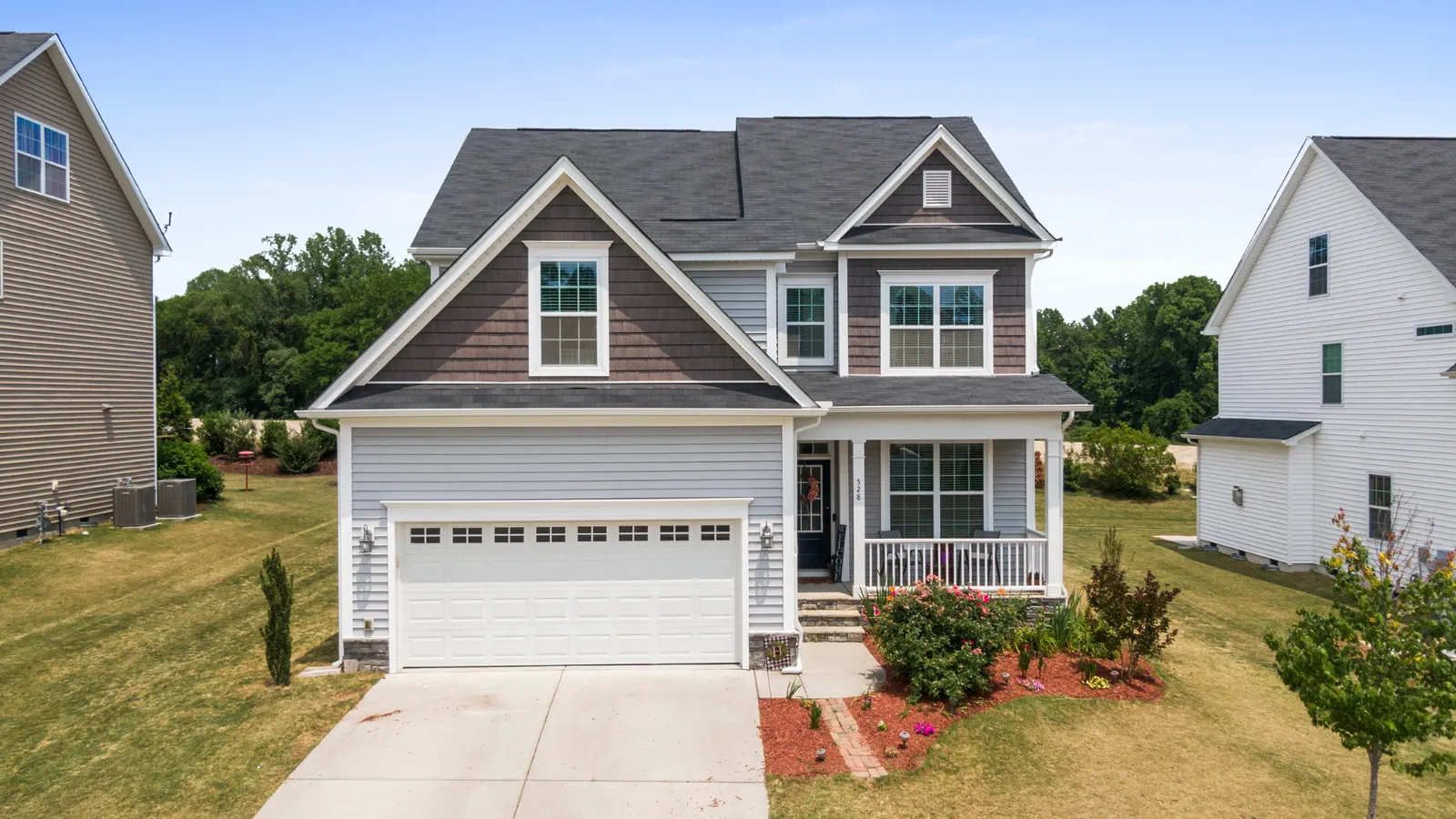 Two-story home with a white garage door on a sunny street