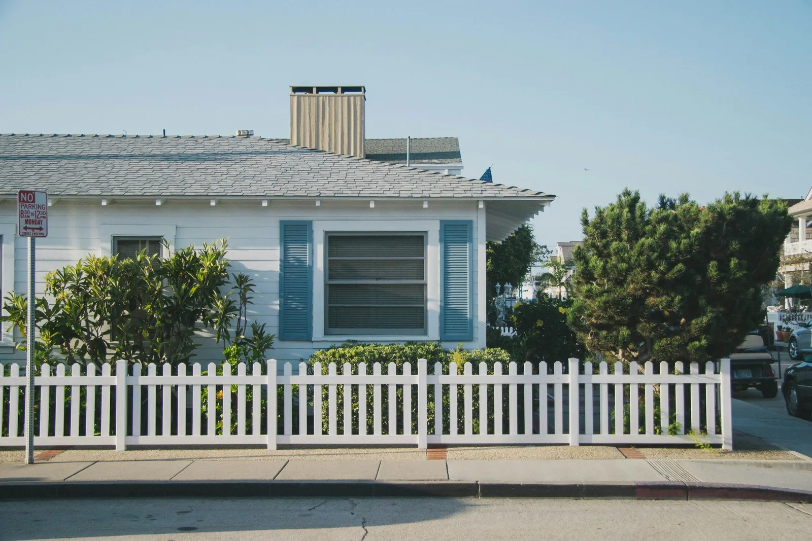 Blue house with an aging roof behind a white picket fence