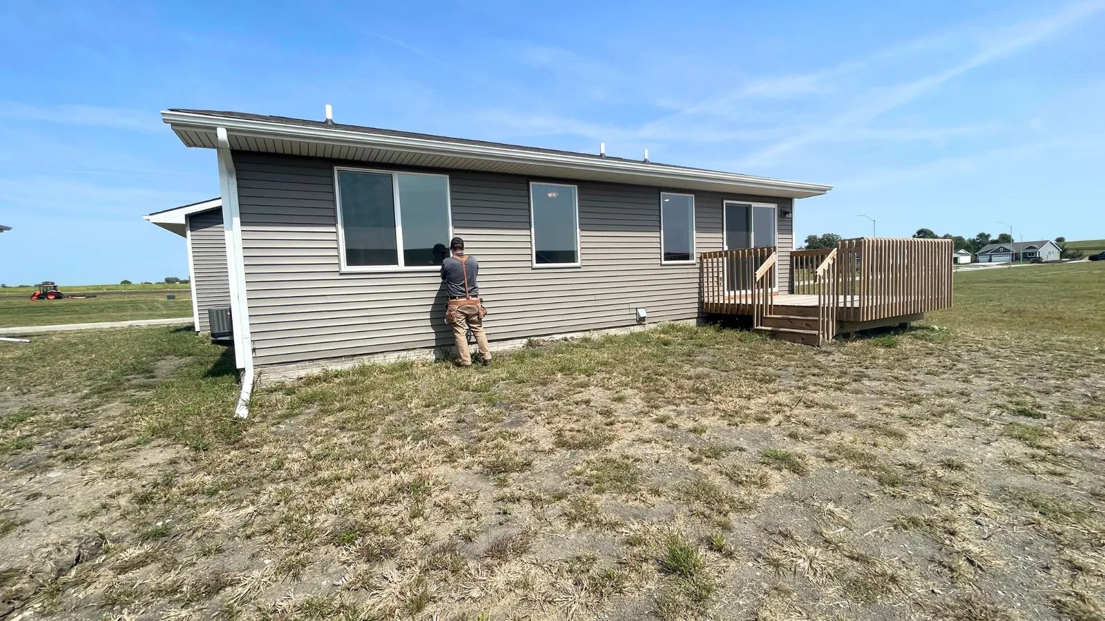 Inspector examining the siding of a gray ranch home