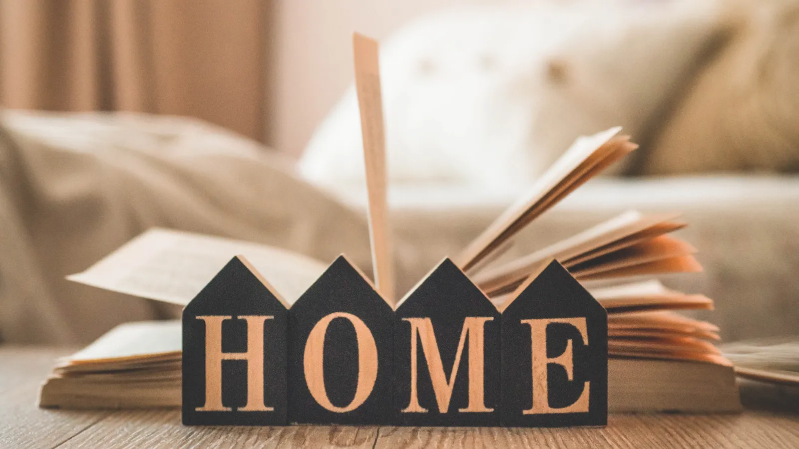 Wooden letters spelling HOME in front of an open book