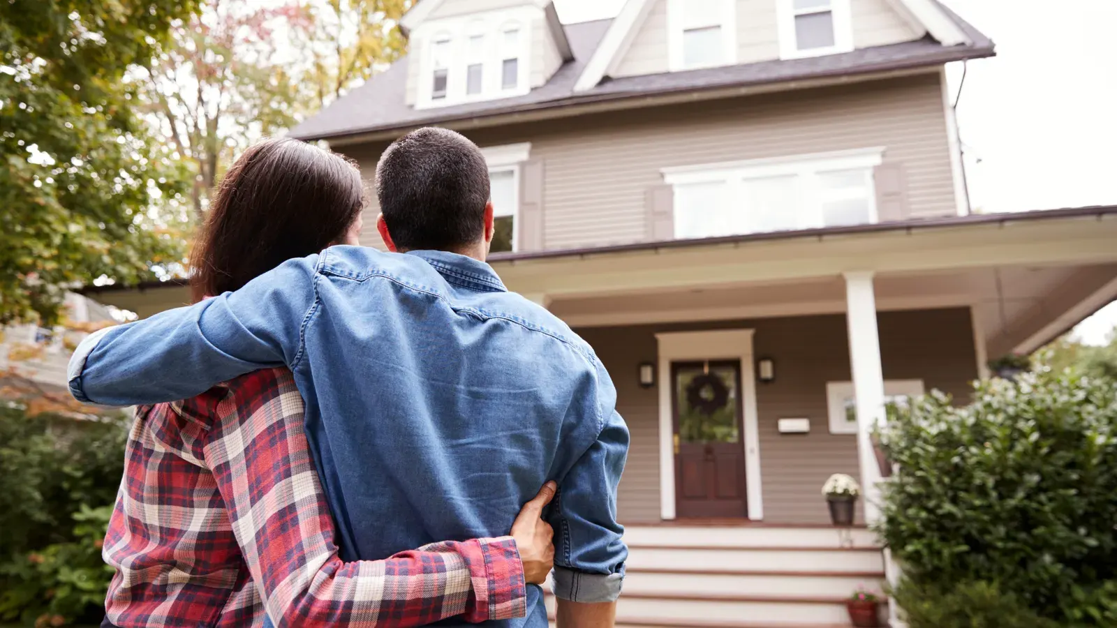 Couple with arms around each other looking at a two-story house