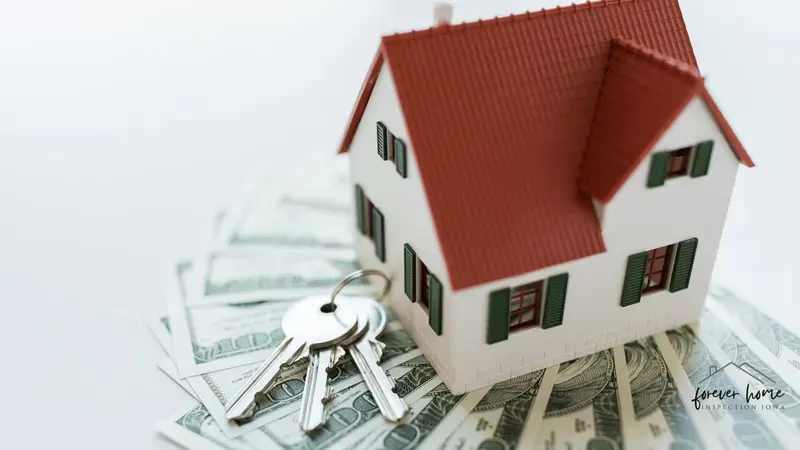 Small model house on a stack of cash with house keys