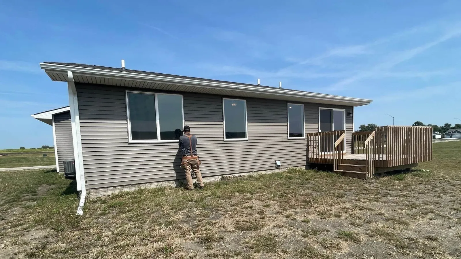 Inspector examining the siding of a gray ranch home