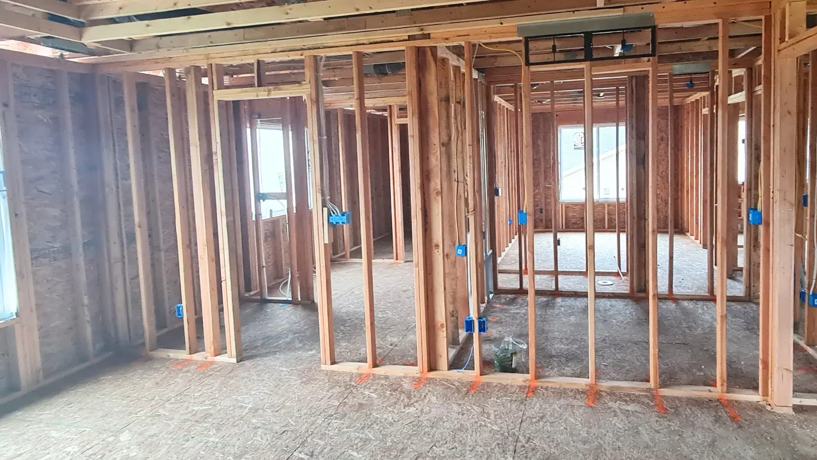 Open stud walls and rough-in wiring inside a home before drywall