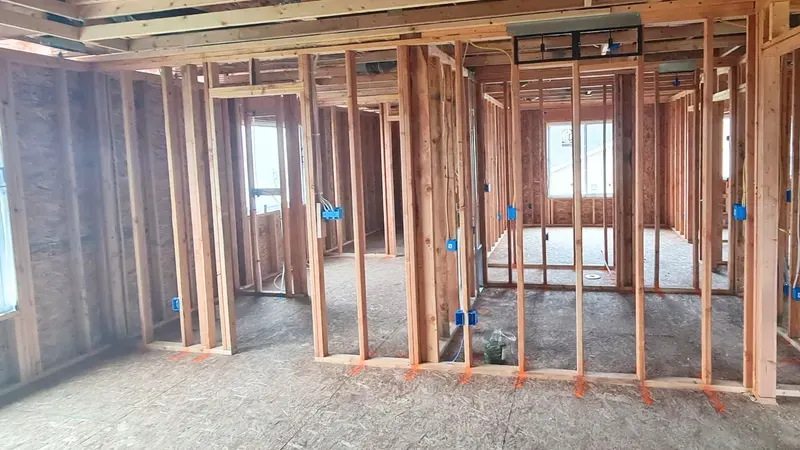Open stud walls and rough-in wiring inside a home before drywall