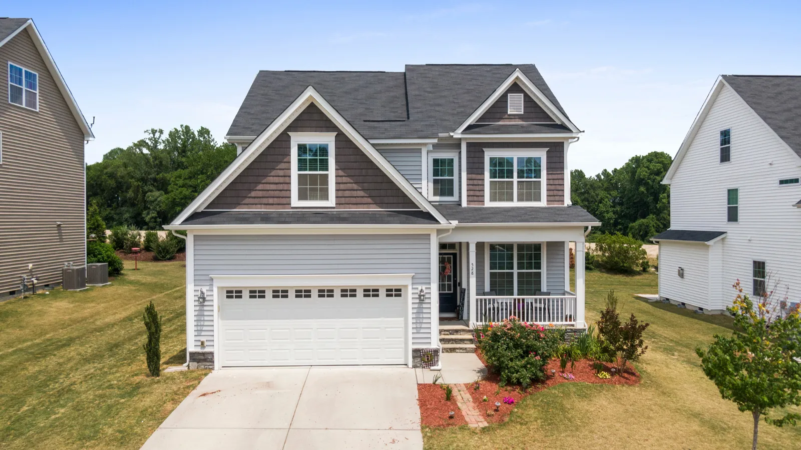 Two-story home with a white garage door on a sunny street