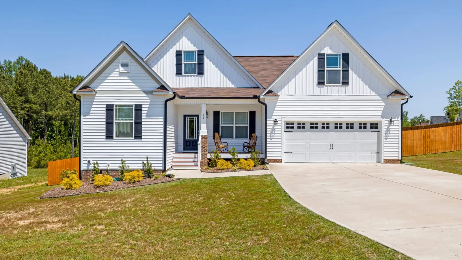White two-story home with a front porch and a long driveway