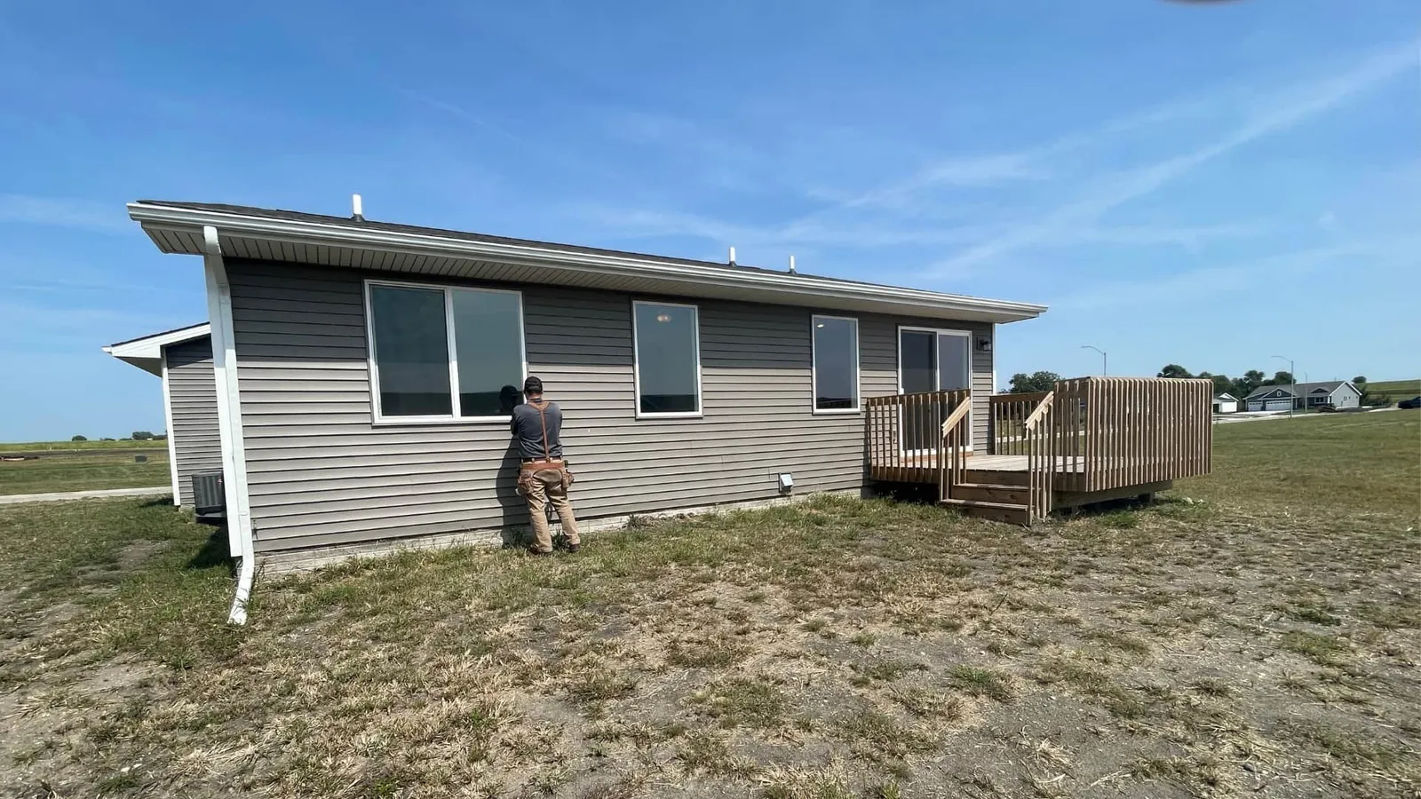 Inspector examining the siding of a gray ranch home