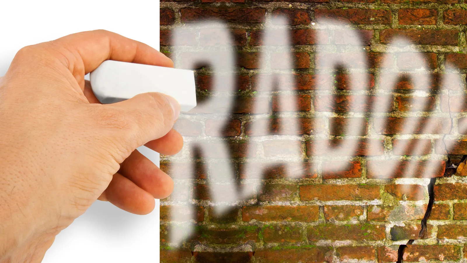 Hand holding a radon test kit next to the word Radon on a brick wall