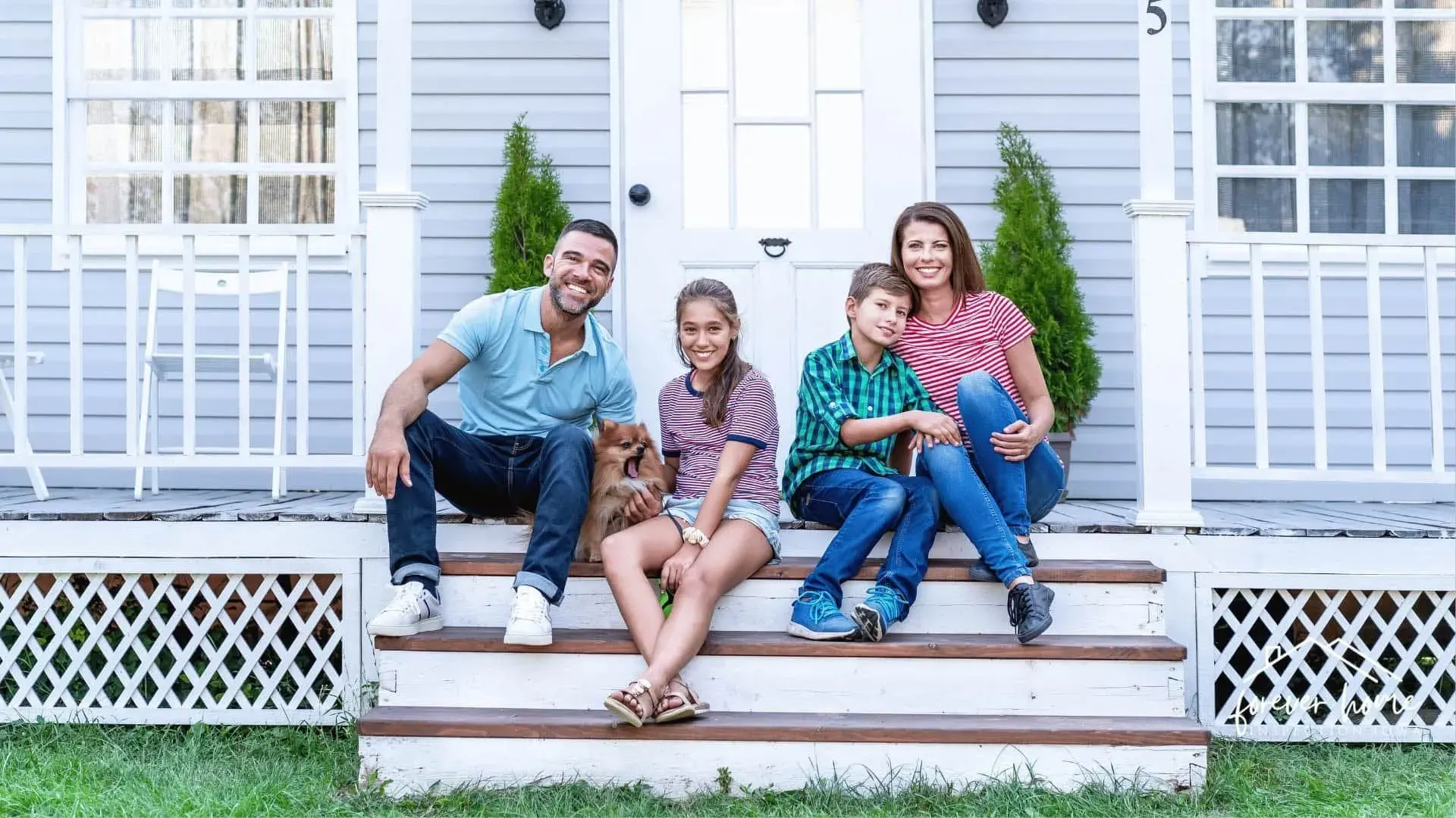 Family of four sitting together on their front porch steps