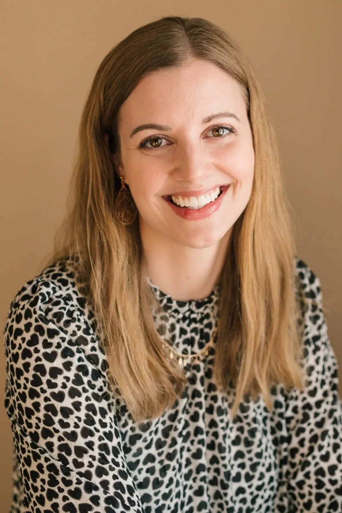 Kalyn Gibson in a leopard-print blouse against a warm tan background