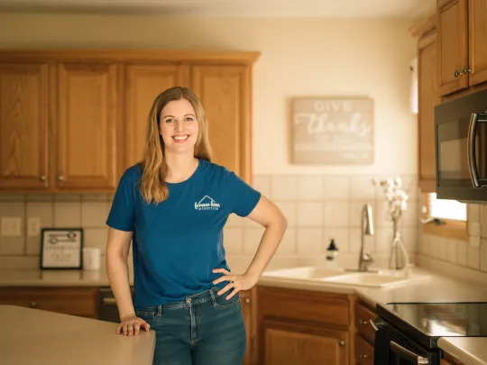 Kalyn Gibson smiling in a kitchen in a blue Forever Home Inspection tee